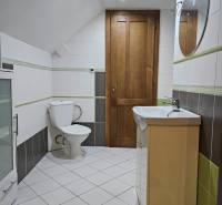 A bathroom with white and green tiles in a family house.