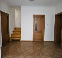 Interior of a family house with ceramic tiles, wooden stairs, and doors with glazing.