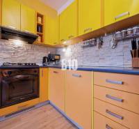 A kitchen in a 2-room apartment with a colorful kitchen unit and a wooden decor floor.