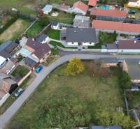 Aerial view of residential plots in Gajary with adjacent road and houses.