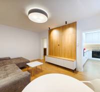 Living room in a two-room apartment with a wooden decor floor, entrance to a white kitchen.