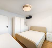 Bedroom in a 2-room apartment with a bed, wardrobe, chest of drawers, and floor with a wooden decor.