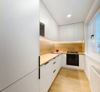 A kitchen in a 2-room apartment with a white kitchen unit and a floor with a wood decor.