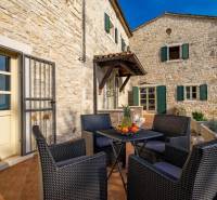Stone facade of a villa in Bale with outdoor seating and fruit on the table.