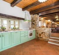 A rural kitchen of a villa with stone walls and a wooden decor floor.