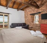 A bedroom in a villa with brick walls, a TV, a sofa, and a large bed.