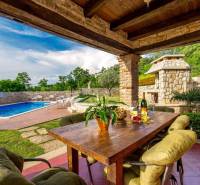 Exterior of a villa in the town of Bale with a pool, table, and natural details.