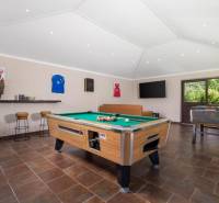 Interior of a villa with a billiard table, leather sofa, and wooden decor flooring.