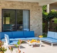 The exterior of the villa in Bale with blue garden seating and a stone wall.