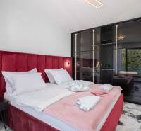 Bedroom in a villa with a bed upholstered in red velvet and a glass wardrobe.
