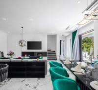 A bright living room in a villa with a marble floor, green armchairs, and modern accessories.
