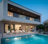 A villa in Bali with a pool, loungers, and a terrace at dusk.