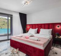 Bedroom in a villa with a large bed and a view of the lake, floor with a marble pattern.