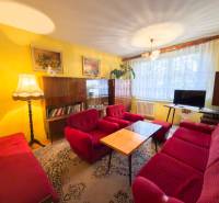 Living room of a three-room apartment with red sofas, carpet, wall decorations, wooden furniture.