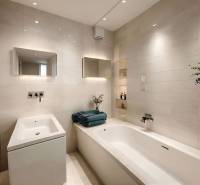 A bathroom with a white bathtub, sink, and mirror in a 3-room apartment.