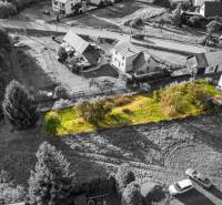 An aerial photograph captures residential plots in the town of Turzovka surrounded by greenery and houses.