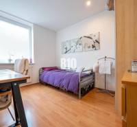 A bedroom in a 4-room apartment with a wood-patterned floor and a purple bedspread.