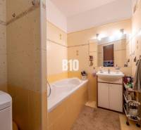 A bathroom with yellow tiles, a bathtub, a sink, and storage space in a 4-room apartment.