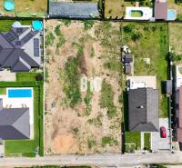 Aerial view of a construction site in Štitáre, surrounded by family houses and swimming pools.