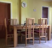 A dining room in a family house with chairs and a table on a floor with a wooden decor.