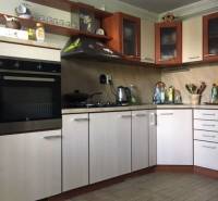 A kitchen in a family house with a wooden decor floor and light cabinets.