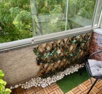 A glazed balcony with wooden decor and plants in a 2-room apartment.