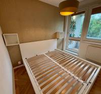 Bedroom with a bed and a large window, 2-room apartment with a wooden decor floor.