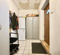The interior of a family house with a refrigerator, a wardrobe, and jackets on a coat rack.