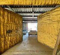 Commercial premises with open doors and a metal roof, a car is visible in the background.