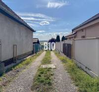 A narrow path between houses in the Pozemky - bývanie area, Nitra, leading to a landscape panorama.