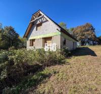 A cottage in Lackov surrounded by greenery, with a blue sky above it.