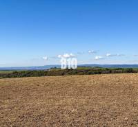 Flat landscape in Lackov with a view of distant hills and a blue sky.