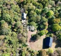 Aerial view of a cabin in Lackov surrounded by dense forest and a clearing.