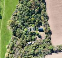 Aerial view of a cabin in Lackov surrounded by forest and fields.