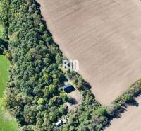 An aerial view of a cottage surrounded by forest and fields in Lackov.