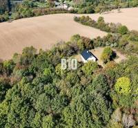 A cottage in Lackov surrounded by forest and fields, a peaceful rural landscape.