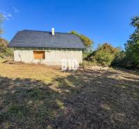A cottage in Lackov surrounded by nature, depicted in a sunny environment.