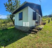 A wooden cottage in the middle of vineyards in Nitra, surrounded by greenery and trees.