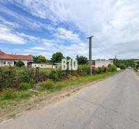 A rural view of residential plots in Bardoňovo near the road and power lines.