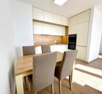 A kitchen in a two-room apartment with a dining table and chairs, flooring with a wooden decor.