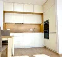 A kitchen in a 2-room apartment with white cabinets and a floor with a wood design.