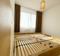 Bedroom with a bed and a lamp in a 2-room apartment with a wood-patterned floor.