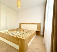 A bedroom with a bed frame and a wooden decor floor in a two-room apartment.