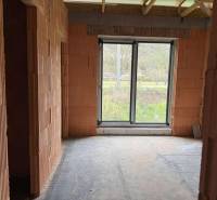 An incomplete structure with brick walls and a large window in a family house.