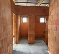 Interior of a family house with brick partitions, two small windows, concrete floor.