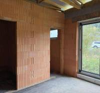 Unfinished interior in a family house with a large window and brick walls.