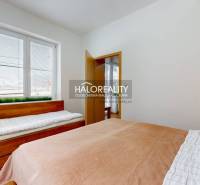 A bedroom in a three-room apartment with two beds and a window with blinds.