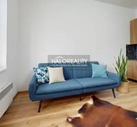 Blue sofa, kitchenette, and wooden decor flooring in a 3-room apartment.