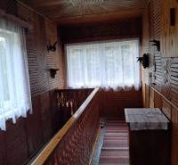 A wooden interior of a family house with decorative railings and carpets in the hallway.
