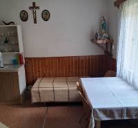 A dining room in a family house with a table, chairs, and religious decorations on the wall.